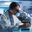 Image of a life sciences lab professional looking down a microscope.